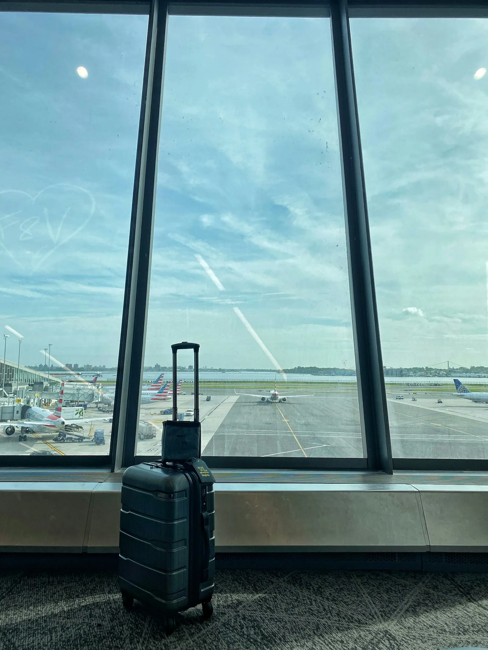 Reisekoffer vor einem großen Flughafenfenster mit Blick auf das Rollfeld
